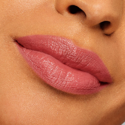 Full lips wearing ColourPop Lippie Stix “It’s Giving,” a rosy mauve pink with a creamy satin sheen, showcasing smooth, even coverage in a close-up swatch against skin for true-to-color shade reference.