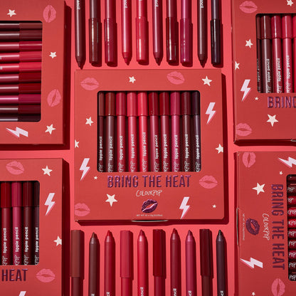 ColourPop Bring The Heat Lippie Pencil set arranged in a flat lay, showcasing creamy lip liners in reds, pinks, and berry tones; boxed and loose pencils surround the main kit on a red background with lips, stars, and lightning graphics.