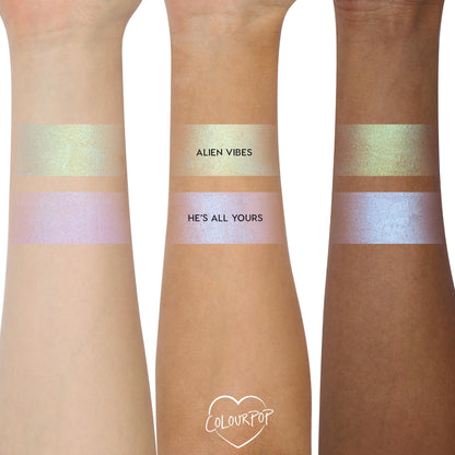 ColourPop Shadow Stix Cute and Feisty swatched on three arms - two bands per arm labeled Alien Vibes (gold‑green shimmer) and He’s All Yours (pink‑lilac blue shift) - showing creamy payoff across light, medium, and deep skin tones.